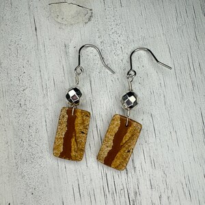 May include: A pair of earrings with brown and white rectangular stone accents and silver metal beads.