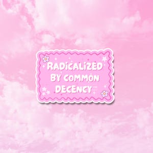 May include: A pink sticker with a scalloped edge and the text "RADICALIZED BY COMMON DECENCY" in white. The sticker has a light pink background with a cloudy sky.
