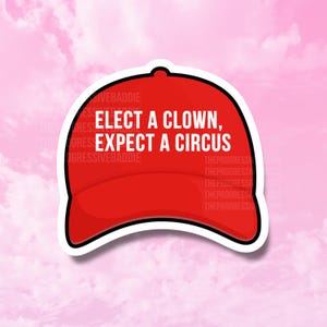 Può includere: Un adesivo a forma di cappellino da baseball rosso con la scritta bianca "ELECT A CLOWN, EXPECT A CIRCUS". L'adesivo ha un bordo bianco e si trova su uno sfondo rosa nuvoloso.