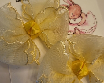 Yellow mesh scalloped bows on metal clips.
