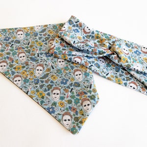 May include: A blue fabric headband and bandana with a repeating pattern of a white mask and flowers. The mask is a popular horror movie character.