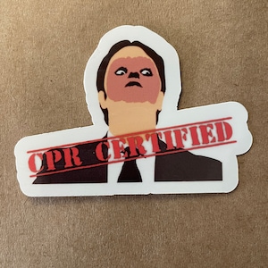 May include: A sticker featuring a cartoon image of a man with a red face and the text "CPR CERTIFIED" in red across the top.