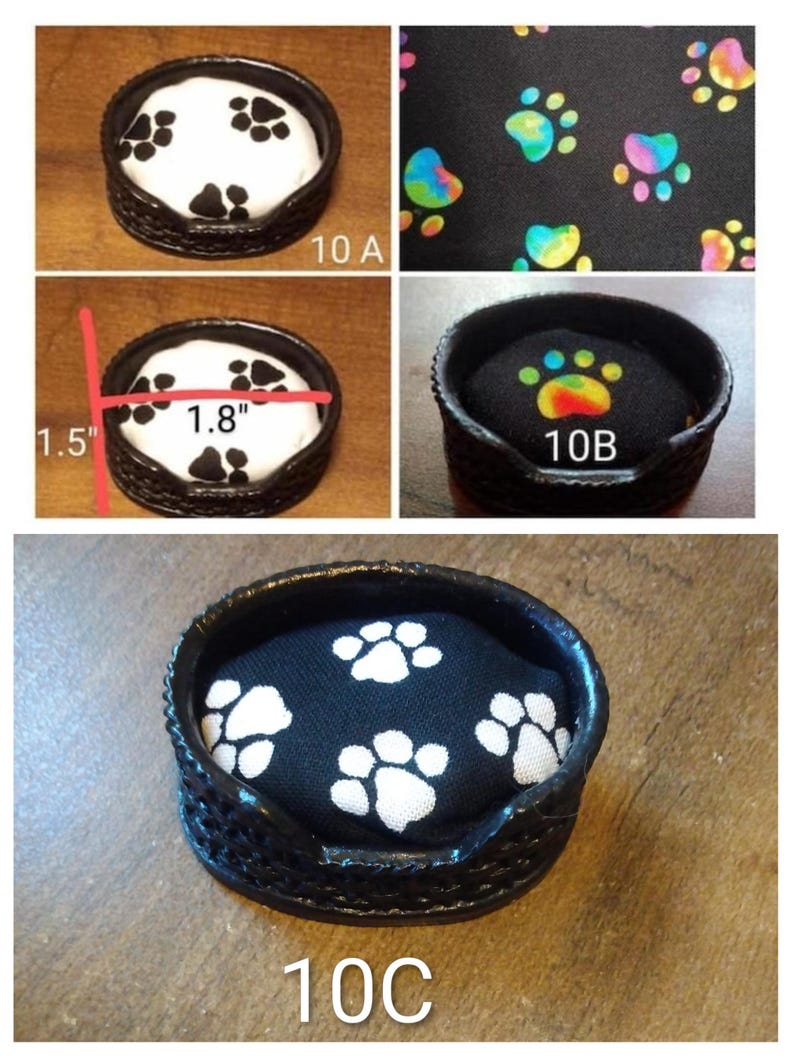 May include: A small, black pet bed with a woven exterior and a paw print design. The bed's interior is black with white paw prints. The bed is 1.8 inches wide and 1.5 inches tall. The text "10 A", "10 B", and "10 C" are visible.