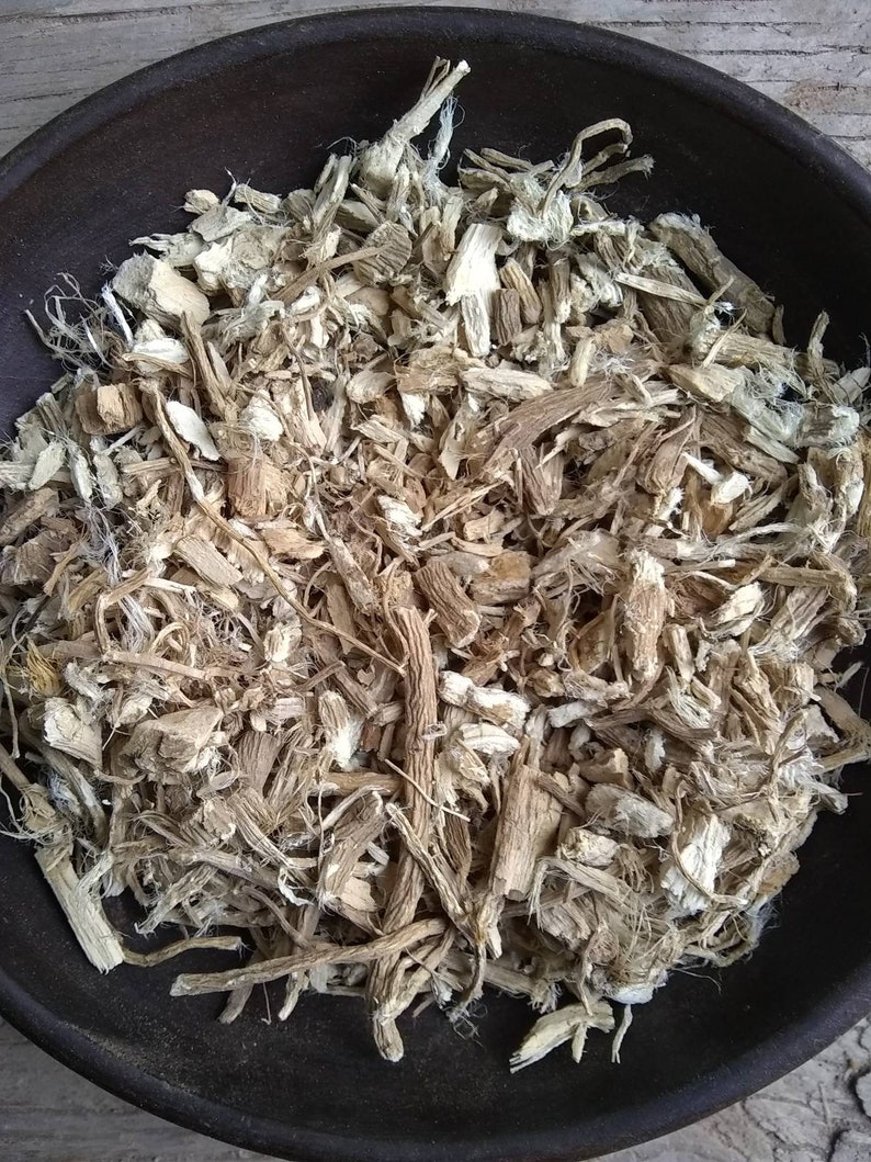 May include: A close-up of a bowl filled with dried, light brown and white root pieces. The root pieces are chopped and shredded, and some are long and thin.