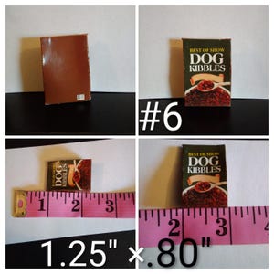 May include: Miniature dog food box labeled "Best of Show Dog Kibbles." The box is brown and green with a picture of dog food. The box measures 1.25 inches by 0.80 inches.