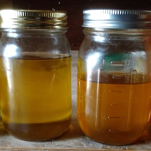 Puede incluir: Cuatro tarros de vidrio con tapas llenos de l&iacute;quidos de diferentes colores. Los tarros est&aacute;n sobre una superficie de madera. Los l&iacute;quidos son verde oscuro, amarillo claro, amarillo oscuro y naranja rojizo.