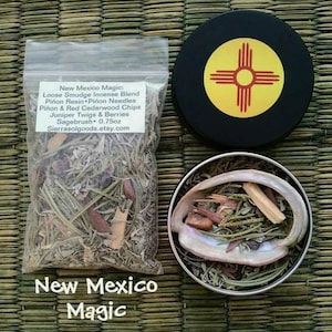 May include: A small bag of loose smudge incense blend with a label that reads "New Mexico Magic: Loose Smudge Incense Blend Piñon Resin * Piñon Needles Piñon & Red Cedarwood Chips Juniper Twigs & Berries Sagebrush * 0.75oz Sierrasolgoods.etsy.com". The bag is sitting on a woven mat with a small metal tin with a lid. The lid has a yellow and red symbol on a black background. The tin is filled with the same incense blend as the bag. The text "New Mexico Magic" is written in large letters below the image.
