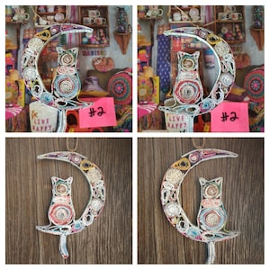 May include: A colorful cat sitting on a crescent moon made of rolled up paper. The moon is decorated with colorful paper and the cat is made of rolled up paper. The background is a wooden surface.