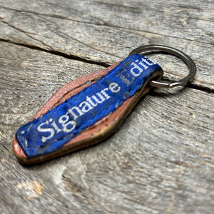 May include: A blue leather keychain with the text "Signature Loft" in white lettering.