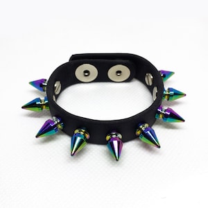May include: Black leather bracelet with rainbow-coloured metal spikes. The bracelet has two snap closures.