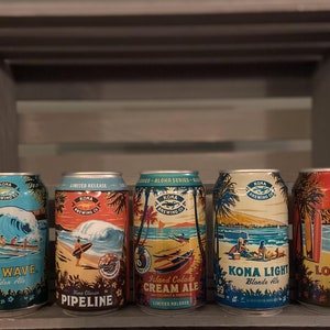 May include: Six aluminum cans of Kona Brewing Company beer. The cans feature different designs with a beach and ocean theme. The cans are labeled with the names "Big Wave Golden Ale", "Pipeline Kona Classic", "Island Colada Cream Ale", "Kona Light Blonde Ale", and "Longboard Island Lager".