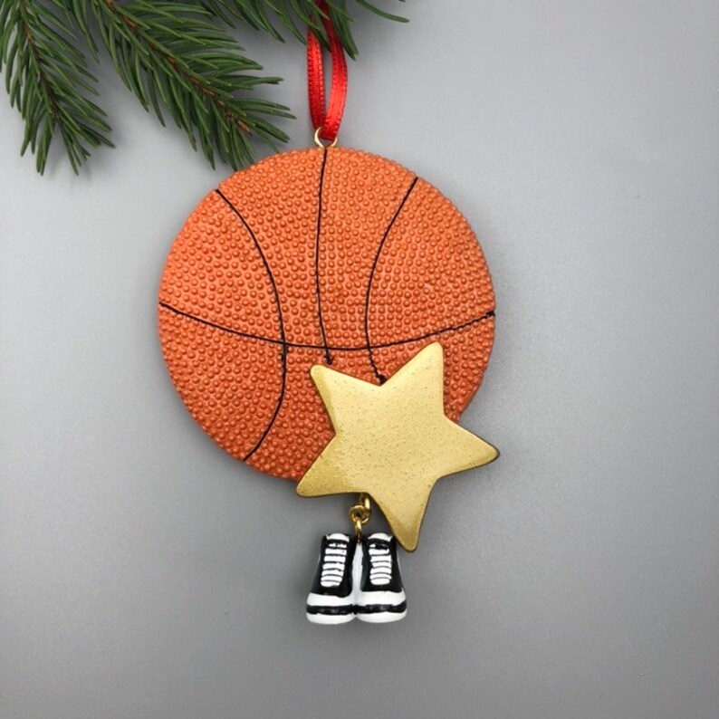 May include: Orange and black basketball Christmas ornament with a gold star and black and white sneakers hanging from it.