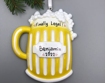May include: Yellow and white beer mug Christmas ornament with the text "Finally Legal!" and "Benjamin 2022".