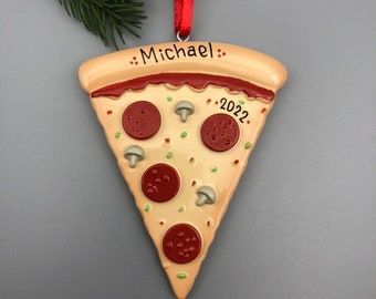 May include: Personalized pizza slice Christmas ornament with the name "Michael" and the year "2022" on a beige background.