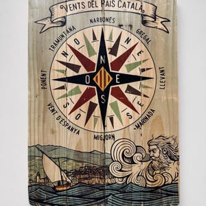Peut inclure: Panneau en bois sur le thème nautique. Le panneau présente une rose des vents avec du texte directionnel en catalan. En dessous, une scène côtière avec un voilier et une figure mythologique. Le panneau indique "VENTS DEL PAÍS CATALA".