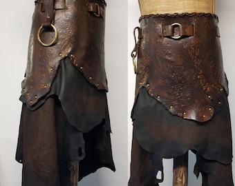 May include: A brown leather skirt with a decorative belt and a layered design. The skirt has a dark brown color and a distressed look.