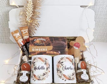 May include: A gift box filled with a variety of treats. Includes two white mugs with floral designs and the names "Michelle" and "Charlie", a box of dark chocolate gingers, coffee packets, a gingerbread man, honey jars, and candles.
