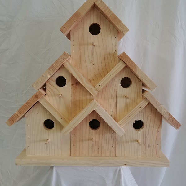 May include: A wooden birdhouse with multiple compartments, each with a round entrance hole. The birdhouse is made of natural wood and has a simple, rustic design.