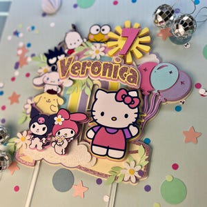 May include: A colorful cake topper featuring Hello Kitty, My Melody, and other cartoon characters. The topper includes a pink number 7, a yellow sun, and the name "Veronica" in pink glitter letters.