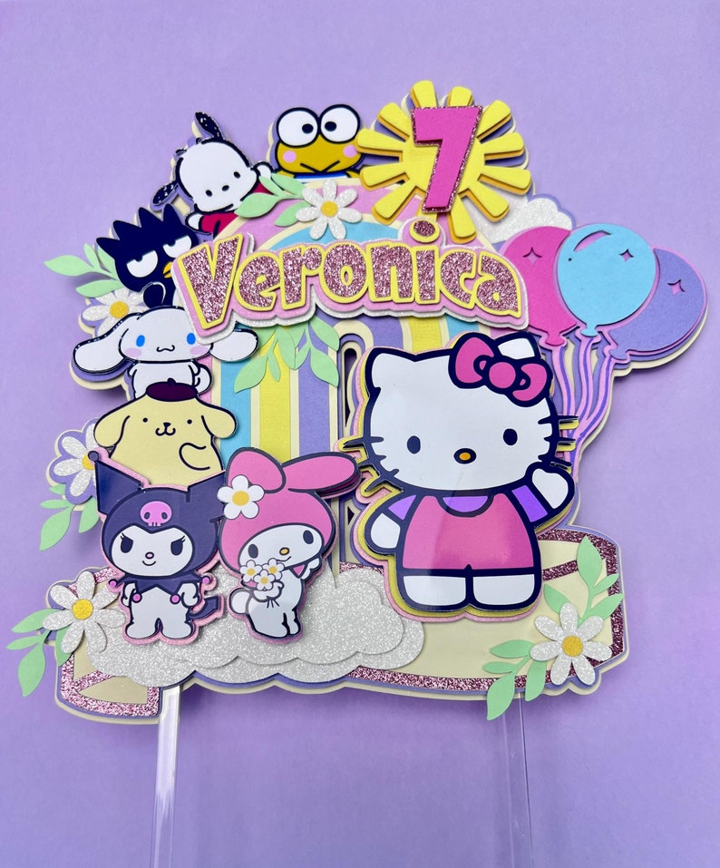 May include: A colorful cake topper featuring Hello Kitty, My Melody, and other popular cartoon characters. The topper is decorated with flowers, a rainbow, and the name "Veronica".