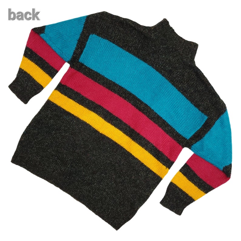 Puede incluir: Un su&eacute;ter negro con rayas horizontales en amarillo, rojo y azul. El su&eacute;ter tiene cuello alto y mangas largas.
