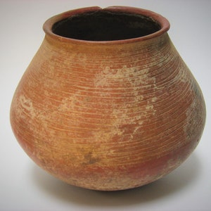 May include: A terracotta pot with a rounded body and a wide opening. The pot has a reddish-brown color and is decorated with horizontal lines.