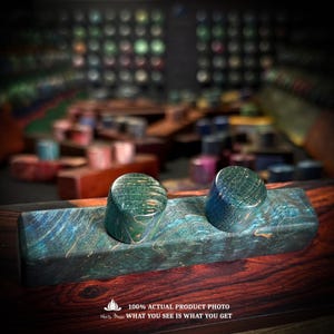 May include: A rectangular block of teal and blue dyed wood featuring two cylindrical knobs on top. The wood displays a prominent swirling grain pattern throughout. Text at the bottom reads: 100% ACTUAL PRODUCT PHOTO WHAT YOU SEE IS WHAT YOU GET.