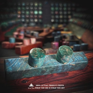 May include: A rectangular block of stabilized wood with a blue and green marbled grain pattern, featuring two cylindrical plugs of the same material attached to the top surface. The text 100% ACTUAL PRODUCT PHOTO WHAT YOU SEE IS WHAT YOU GET is visible.