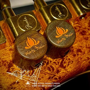 May include: Two dark brown wooden guitar knobs featuring an orange flame logo and the text Wants Music, positioned on a burl wood guitar body with gold tuning pegs. The text 100% ACTUAL PRODUCT PHOTO WHAT YOU SEE IS WHAT YOU GET is visible.