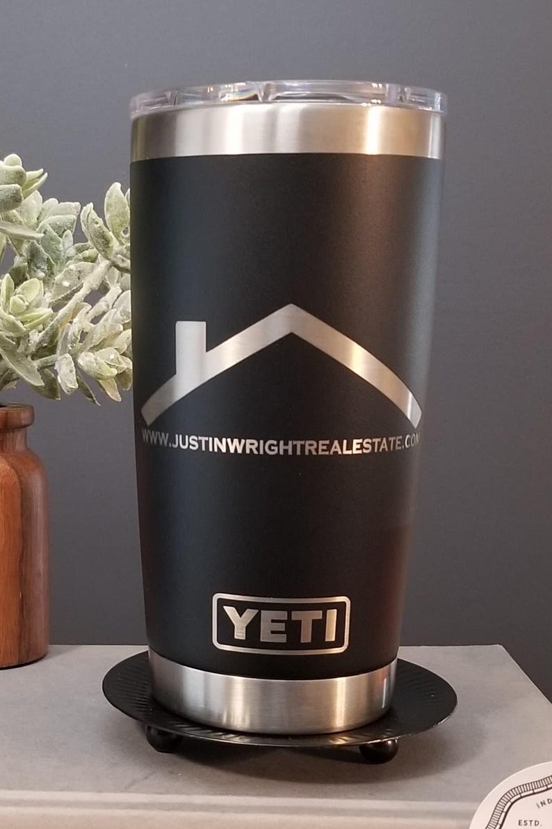May include: Black insulated tumbler with a silver rim and lid. The tumbler features a silver house logo and the text "www.justinwrightrealestate.com". The brand name "YETI" is displayed at the bottom.
