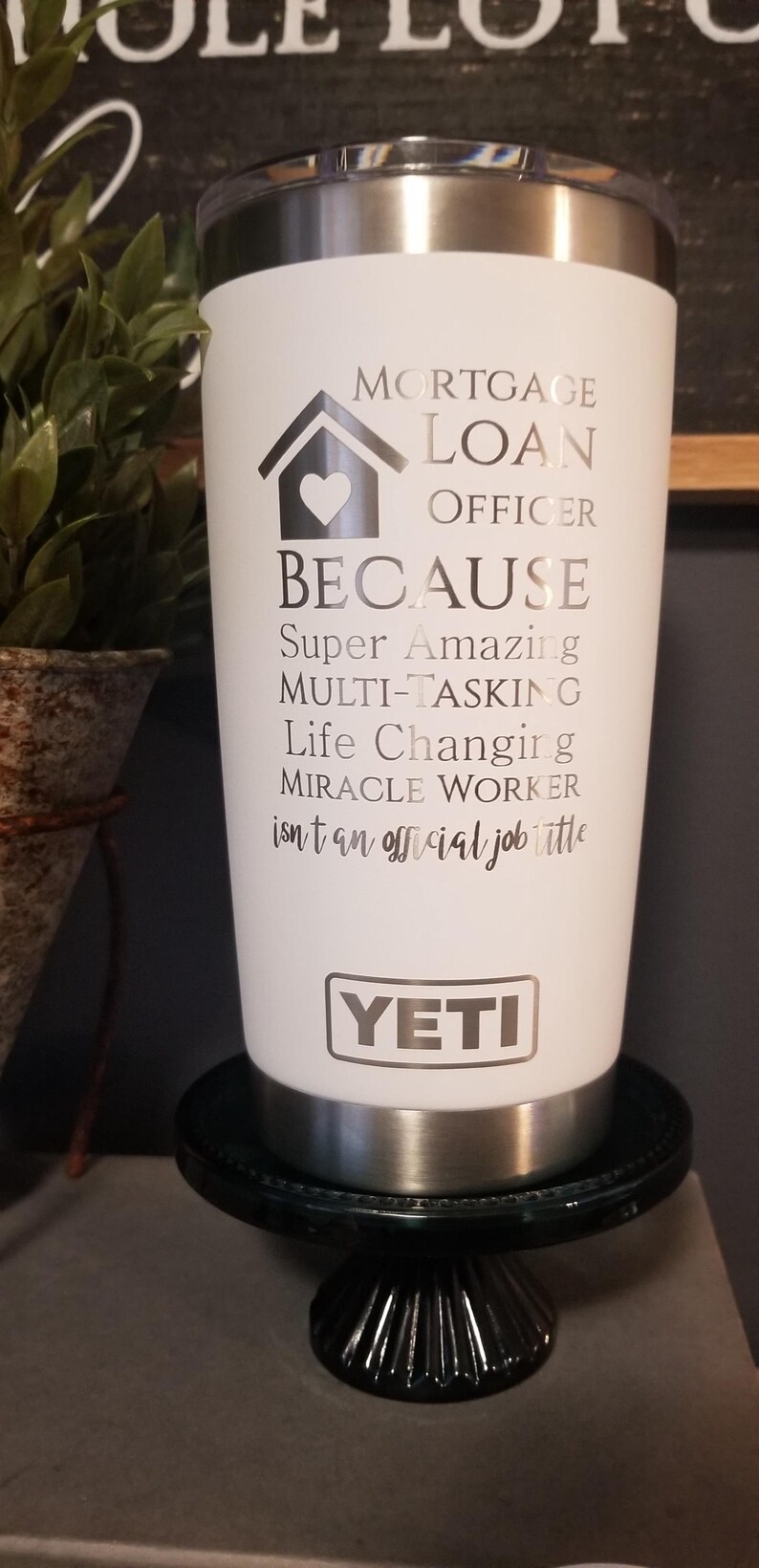 May include: White Yeti tumbler with silver accents, featuring text that reads "MORTGAGE LOAN OFFICER BECAUSE Super Amazing MULTI-TASKING Life Changing MIRACLE WORKER." The tumbler is on a black decorative stand.