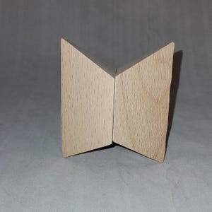 May include: A wooden butterfly-shaped object made of two triangular pieces joined together. The object is light brown in color and has a smooth, polished finish.