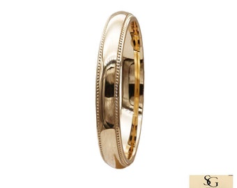May include: A simple gold wedding band with a slightly rounded edge and a beaded detail around the edge.