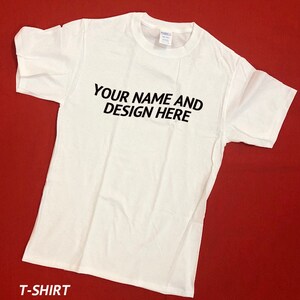 Peut inclure: T-shirt blanc avec le texte "YOUR NAME AND DESIGN HERE" imprim&eacute; en noir sur le devant.