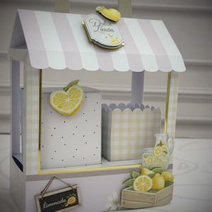 May include: A decorative paper stand shaped like a small shop with a striped roof, featuring a sign that reads Dulce Limón. The structure includes a white box with black dots, a yellow gingham container, and illustrations of lemons and lemonade.