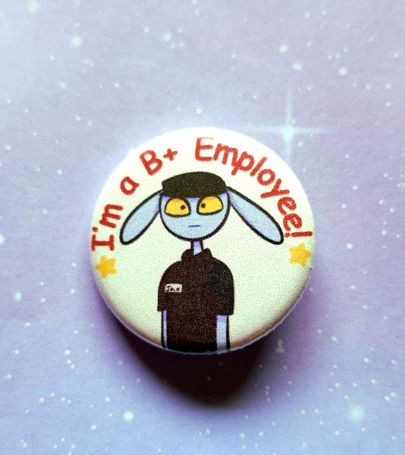 K&ouml;nnte beinhalten: Ein runder Button mit dem Text "I'm a B+ Employee!" in Rot. Der Button zeigt einen Cartoon-Alien-Charakter mit blauer Haut, gelben Augen und einer schwarzen Uniform. Zwei gelbe Sterne sind ebenfalls abgebildet.