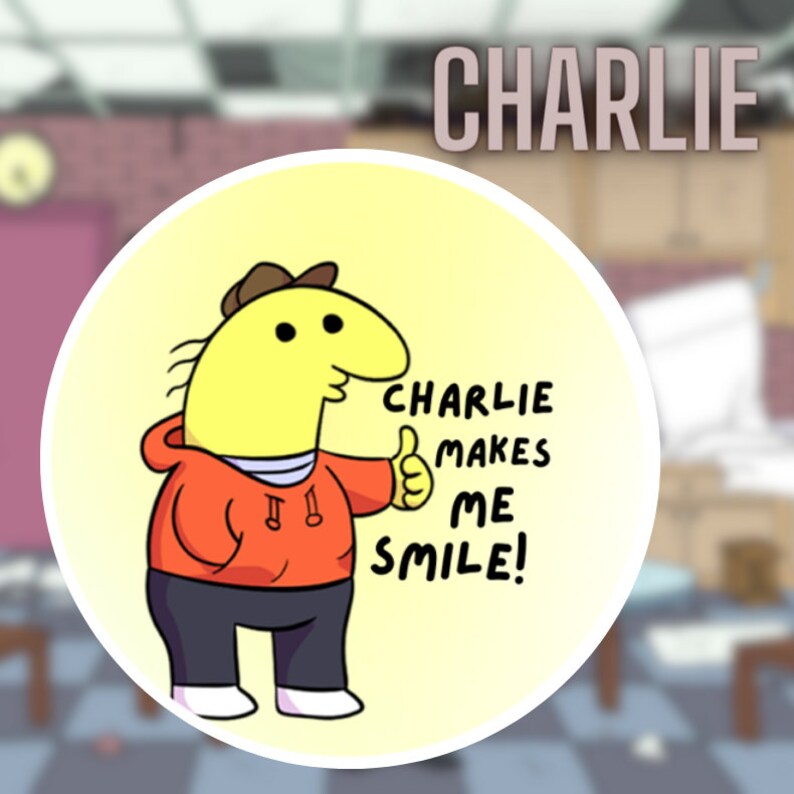 Digital version of the Charlie button against a blurred image of the Smiling Friends office. Two fingers hold up the small button. The text on the button says Charlie Makes Me Smile!