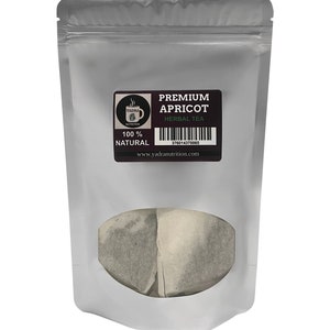 May include: A silver pouch with a clear window showing two tea bags. The pouch has a label that reads "PREMIUM APRICOT HERBAL TEA 100% NATURAL www.yadranutrition.com" with a barcode and a small logo.