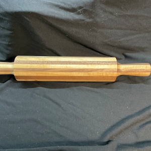 May include: A wooden rolling pin with alternating stripes of light and dark wood.