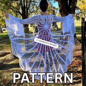 May include: A white crochet cardigan featuring an intricate spiderweb pattern that radiates from the center back, with long, flared sleeves and an open front design. The garment includes a watermark label reading CHIAROSCUROSITY.