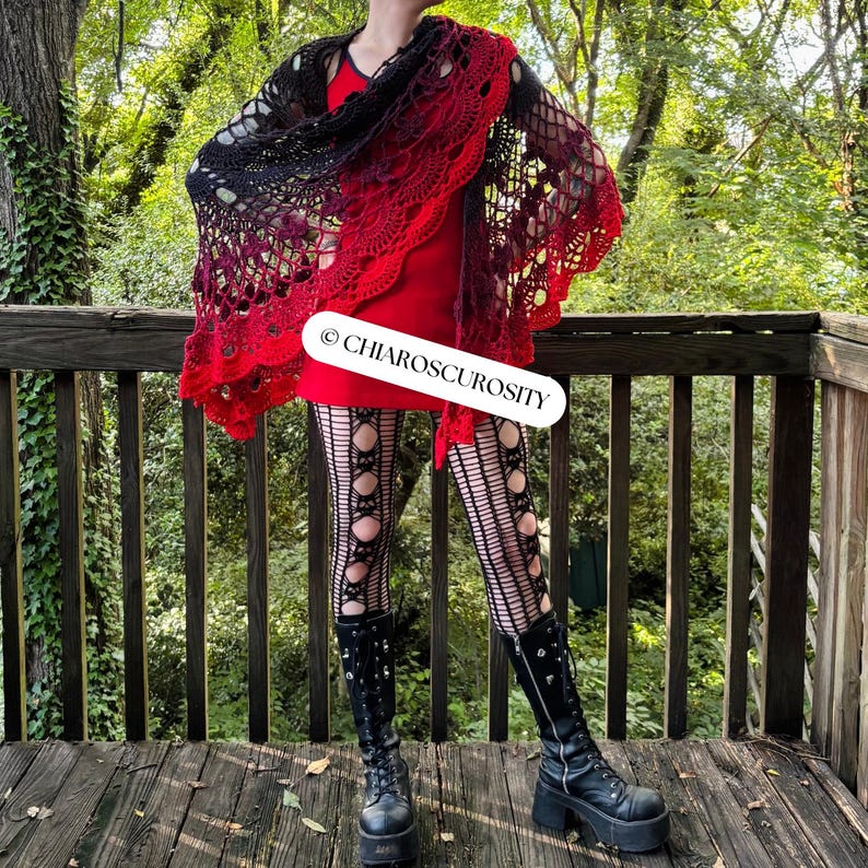 May include: A black to red gradient crocheted shawl worn over a red dress. The image also shows black tights with circular cutouts and black platform boots. The text "&copy; CHIAROSCUROSITY" is visible. The scene is set outdoors.