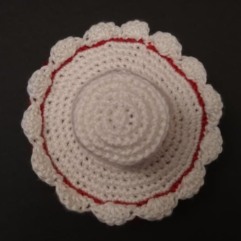 May include: White crocheted sun hat with a red trim and a scalloped edge.
