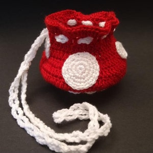 May include: Red crocheted drawstring bag with white polka dots and a white crocheted drawstring.