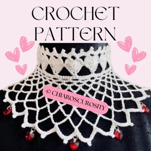 May include: White crochet collar with a delicate lace pattern and red crystal beads. The collar features a repeating heart design and the text "@chiaroscurosity".