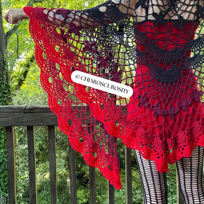 May include: A red and black crochet shawl with a scalloped edge. The shawl features a floral pattern and is draped over a person. The text "&copy; CHIAROSCUROSITY" is visible on the shawl.