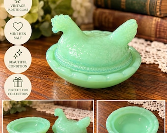 May include: A light green jadeite glass mini hen salt cellar featuring a detailed hen-shaped lid that rests on a matching scalloped base. The translucent glass has a smooth finish and depicts a nesting hen with textured feather details.