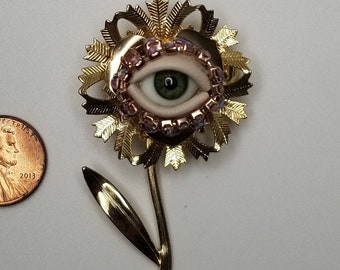 Fancy Flower Wink - Gold toned vintage brooch + glass doll eye. OOAK mixed media jewelry. Floral fantasy art.