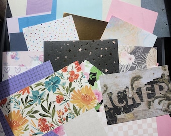 May include: A collection of rectangular paper sheets featuring diverse designs including solid pastel colors, gold foil, polka dots, black with gold stars, floral patterns, grid prints, heart motifs, and a weathered texture with the visible text "CKER".