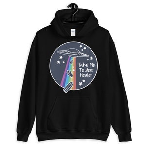 May include: Black hoodie with a graphic of a UFO with a rainbow beam of light and crystals falling from it. The text "Take Me To Your Healer" is written in white on a blue circle.