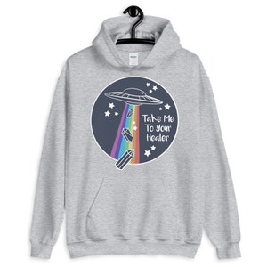 May include: A gray hoodie with a graphic of a UFO flying over a rainbow with crystals falling from it. The text "Take Me To Your Healer" is written below the UFO.
